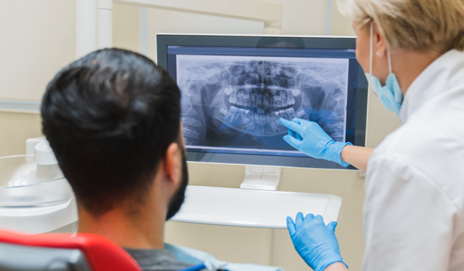 Dentist reviewing panoramic X-ray with patient in clinical office setting.